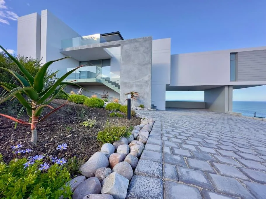 Modern white coastal home with landscaped gardens and ocean view beyond