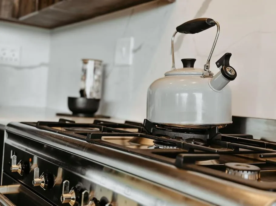 Modern stovetop with cream kettle and cookware in bright kitchen