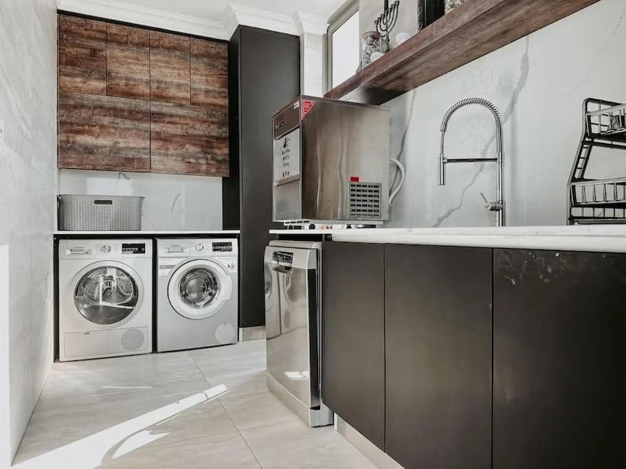 Modern kitchen with washing machines, sink, and dark cabinetry throughout
