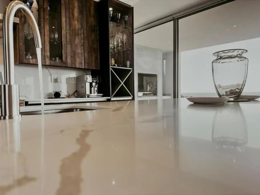 Modern kitchen with dark cabinetry, white countertops, and sleek faucet