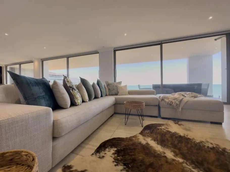 Spacious lounge with sectional sofa overlooking ocean views through floor-to-ceiling windows