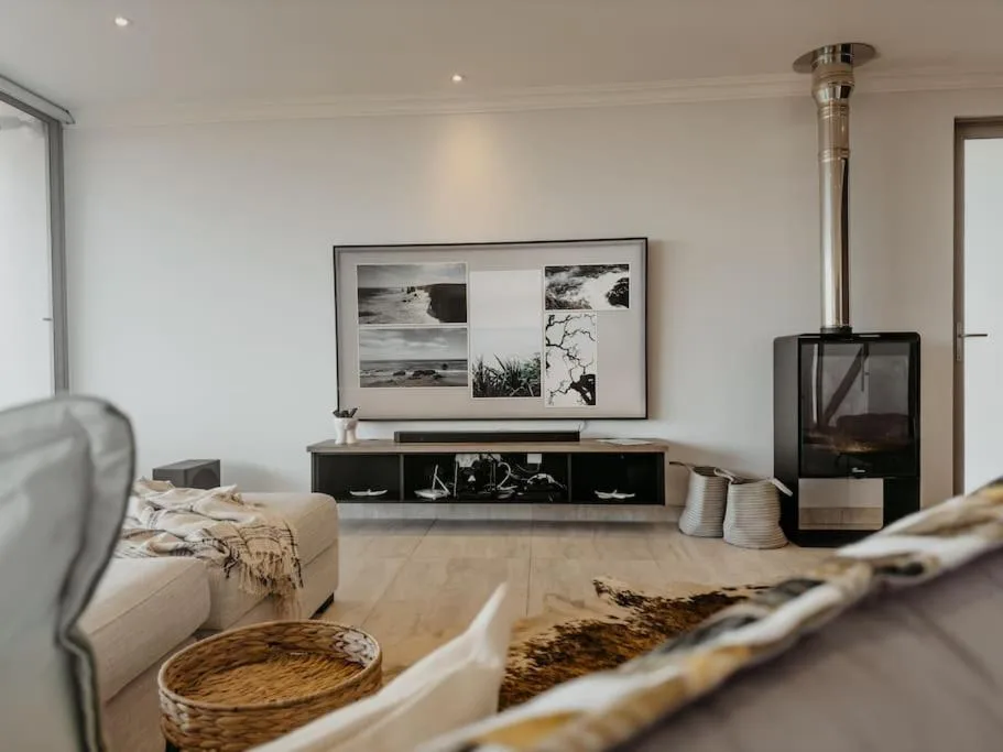 Modern living room with fireplace, TV, and coastal artwork displayed on wall