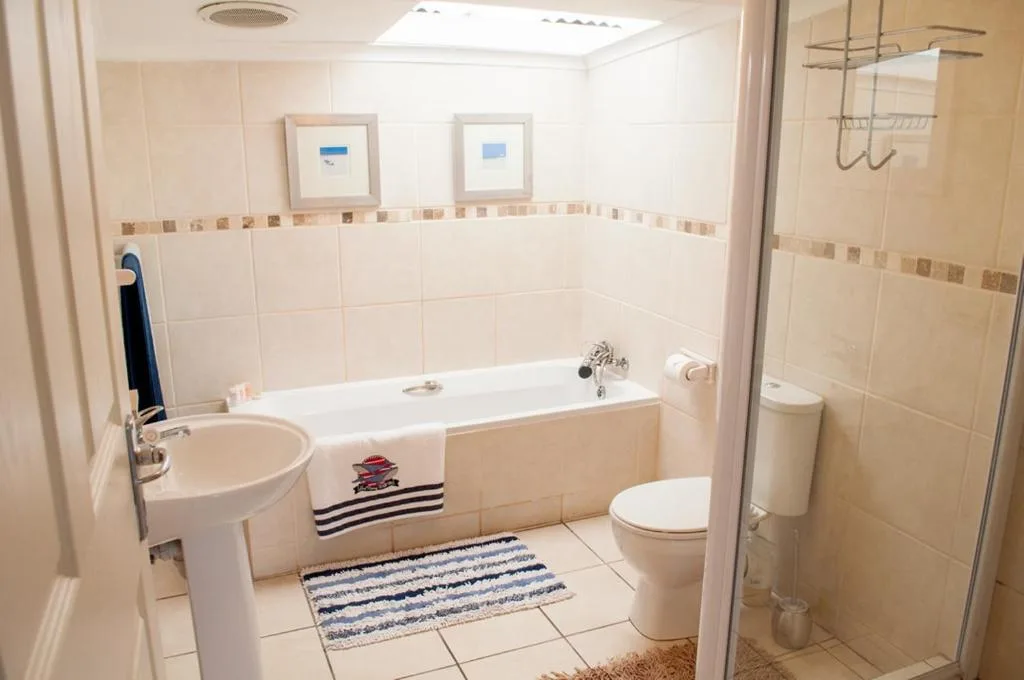 Clean bathroom with bathtub, sink, toilet, and glass shower enclosure