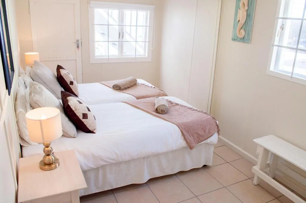 Bright bedroom with double bed, crisp white linens, and warm bedside lighting