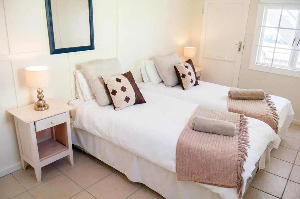 Bright bedroom with two twin beds, decorative pillows, and bedside lamp