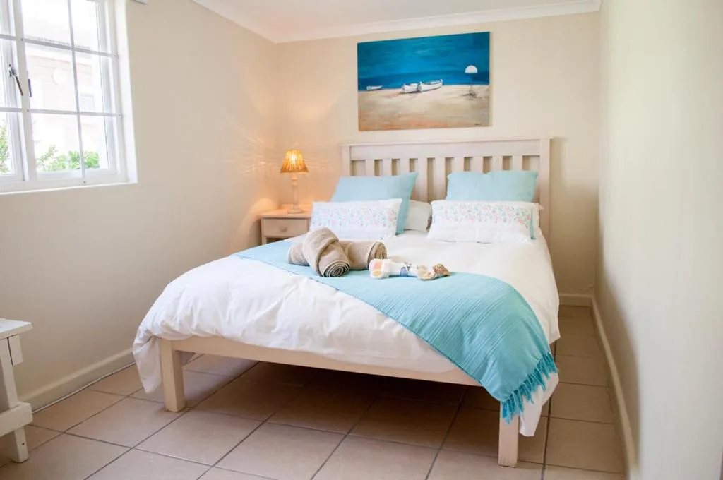 Bright bedroom with double bed, turquoise accents, coastal artwork