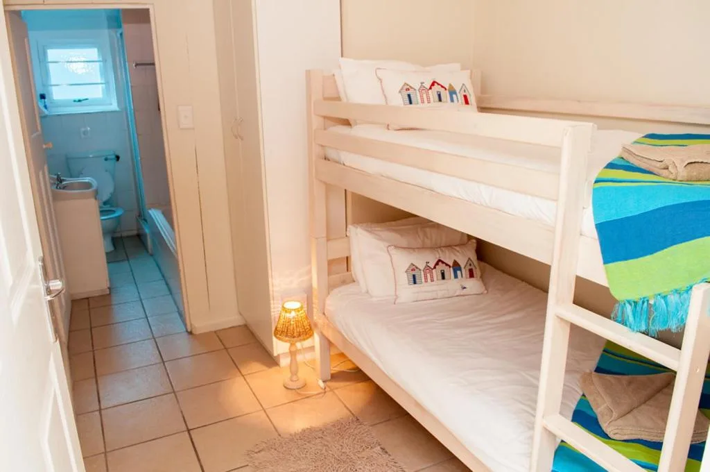 Bright bedroom with wooden bunk beds and beach hut cushions