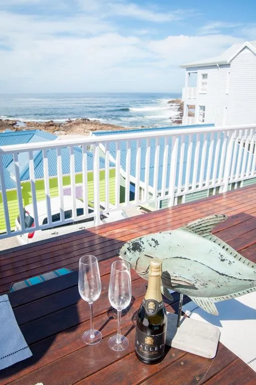 Wooden deck with champagne glasses, ocean views, and white railing