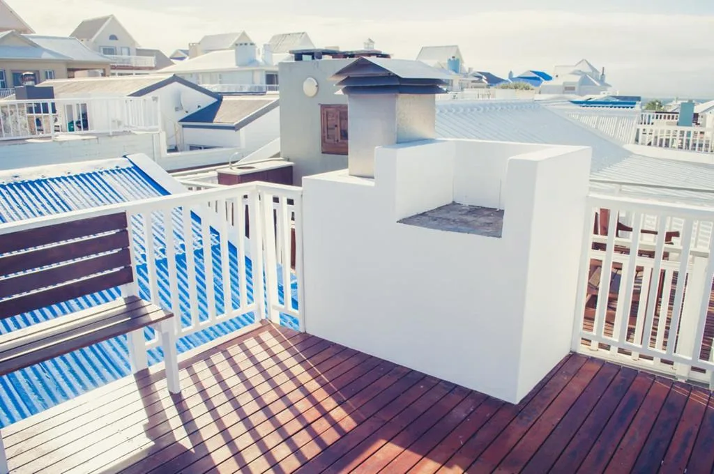 Rooftop deck with white walls, blue railings, and coastal neighborhood views