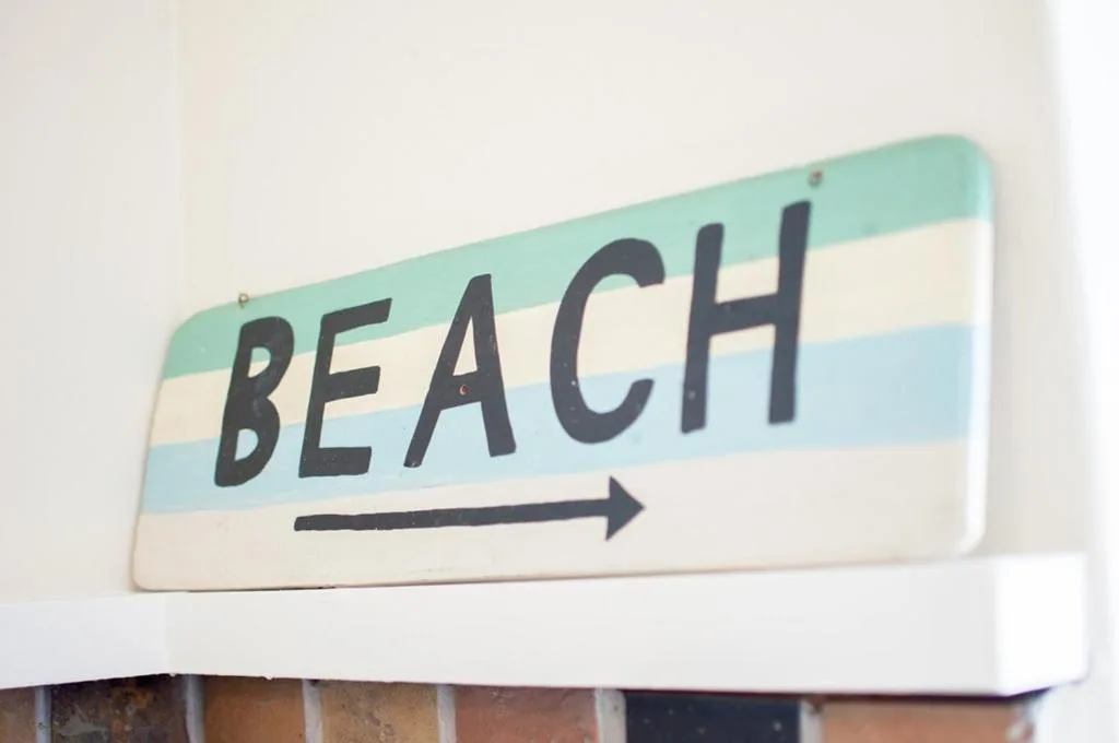 Wooden beach directional sign with pastel stripes and arrow