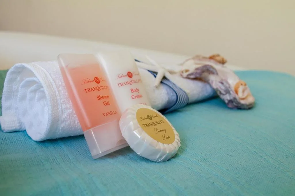 Luxury toiletries and fluffy white towels arranged on turquoise surface