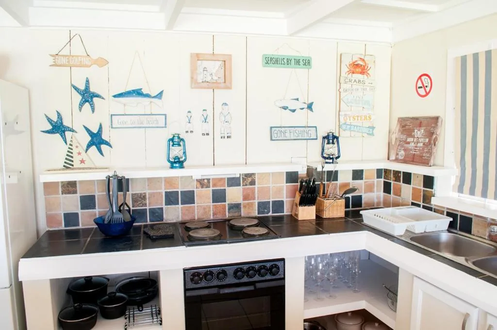 Coastal-themed kitchen with black stove, colorful tile backsplash, nautical wall decor