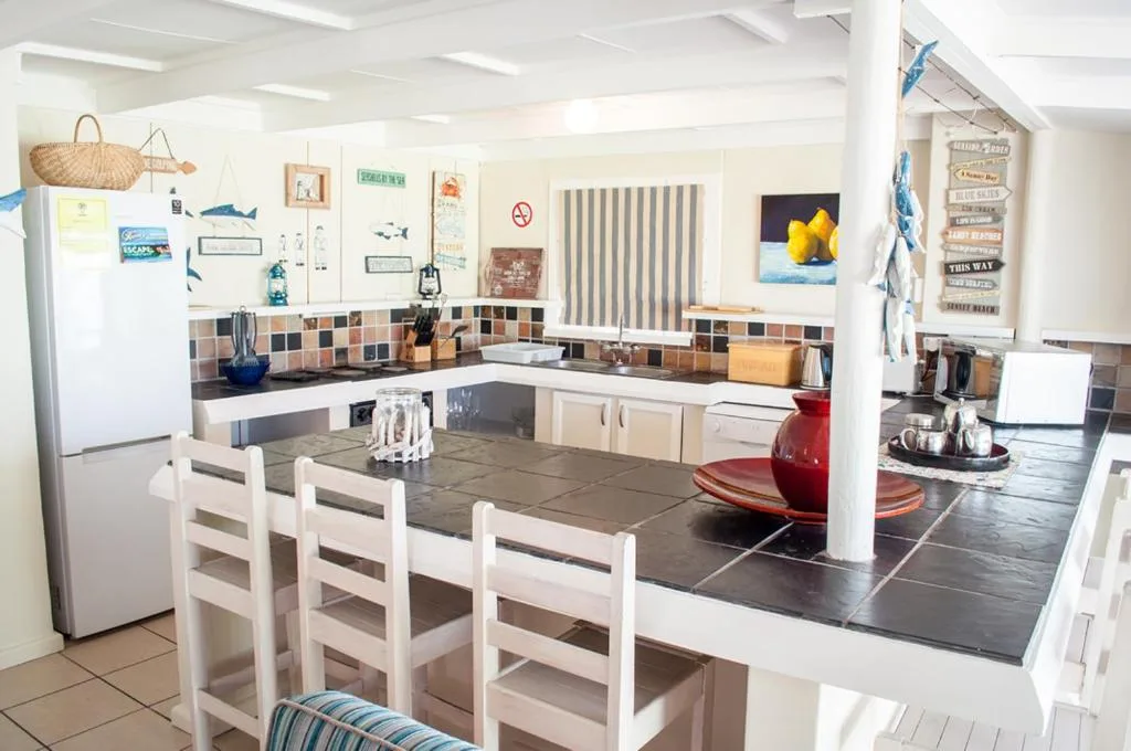 Bright kitchen with colorful tile backsplash, white cabinetry, and dining island seating