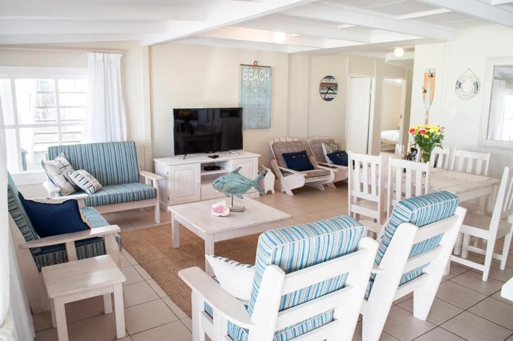 Bright, airy lounge with striped sofas, TV, and coastal decor