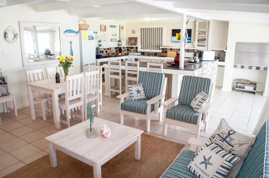 Open-plan lounge with white furniture, striped cushions, and sea-themed decor