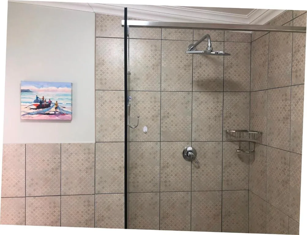 Modern walk-in shower with glass enclosure and decorative beach artwork