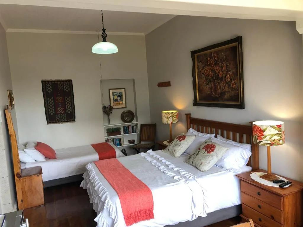 Spacious bedroom with double bed, single bed, wooden furniture and artwork