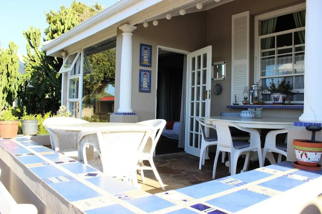 Shaded patio with white furniture, blue tile accents, and garden views