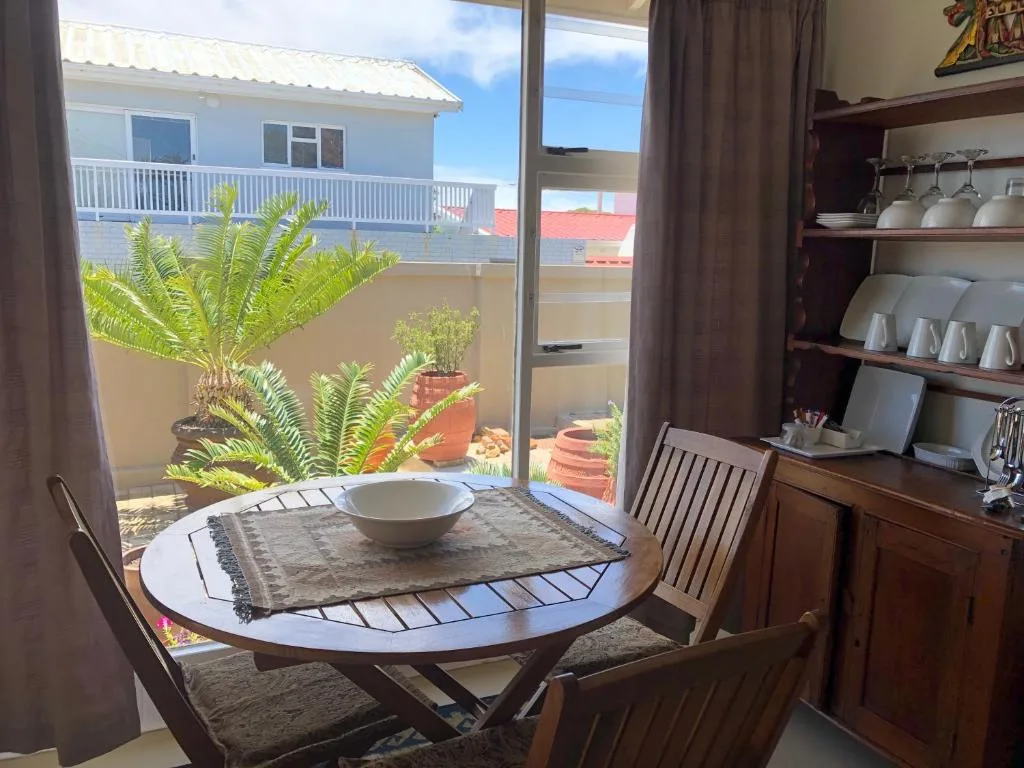 Dining table with potted plants visible through glass doors to deck