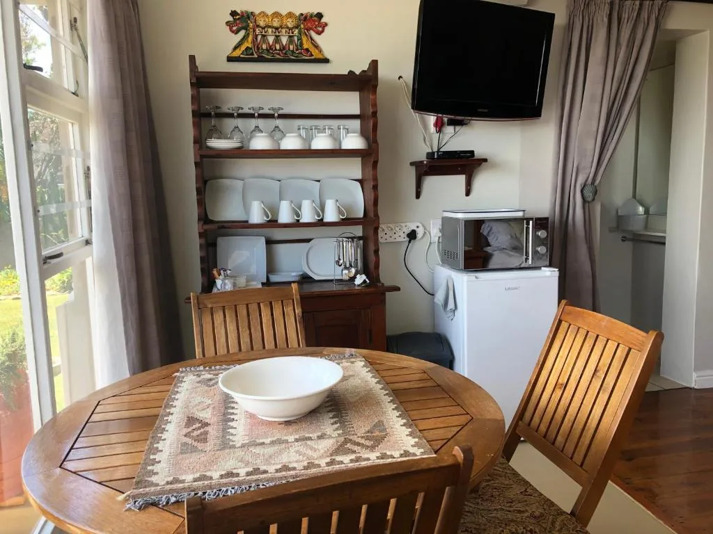 Wooden dining table with chairs, kitchen appliances visible in background