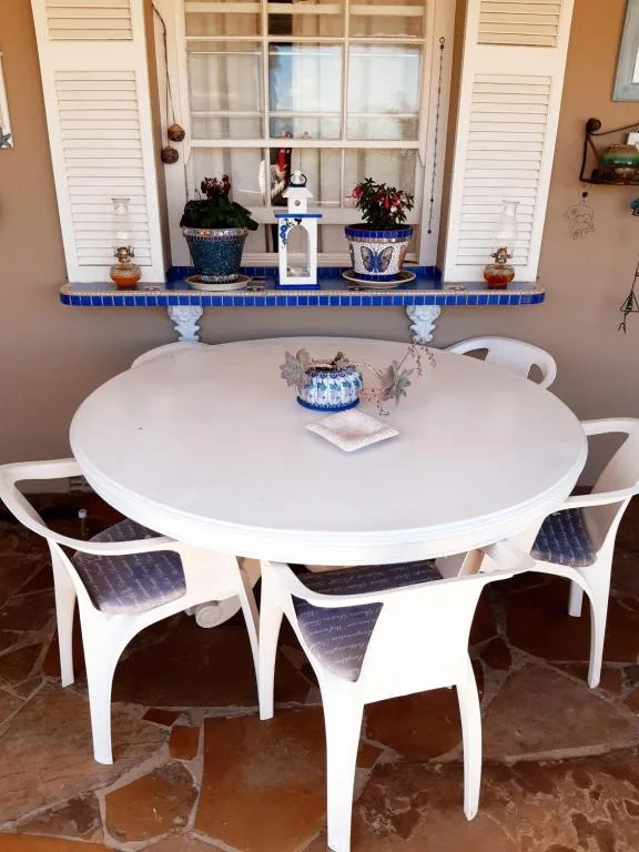 Round white dining table with blue upholstered chairs and window view