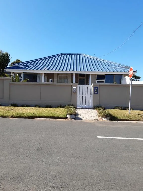 Modern white house with distinctive blue metal roof and surrounding fence