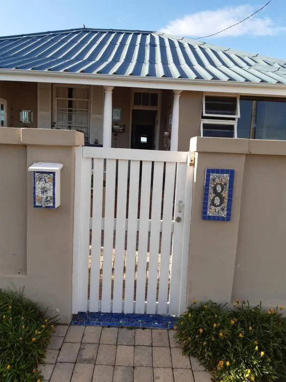Front entrance with white gate and corrugated metal roof structure