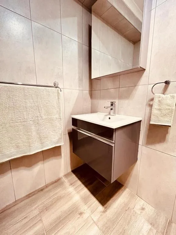 Modern bathroom with vanity sink, mirror, and cream towel rail