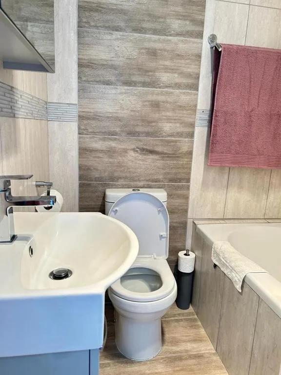Modern bathroom with white sink, toilet, and rose-colored towel on wall