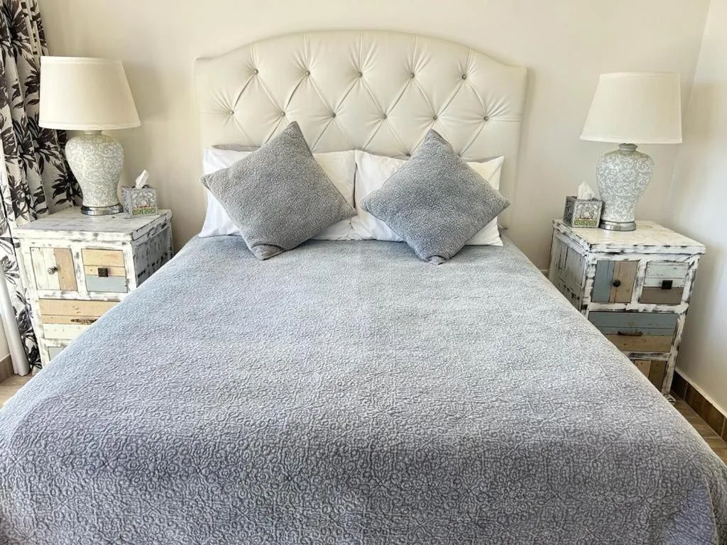 Master bedroom with quilted headboard, gray bedding, and matching nightstands
