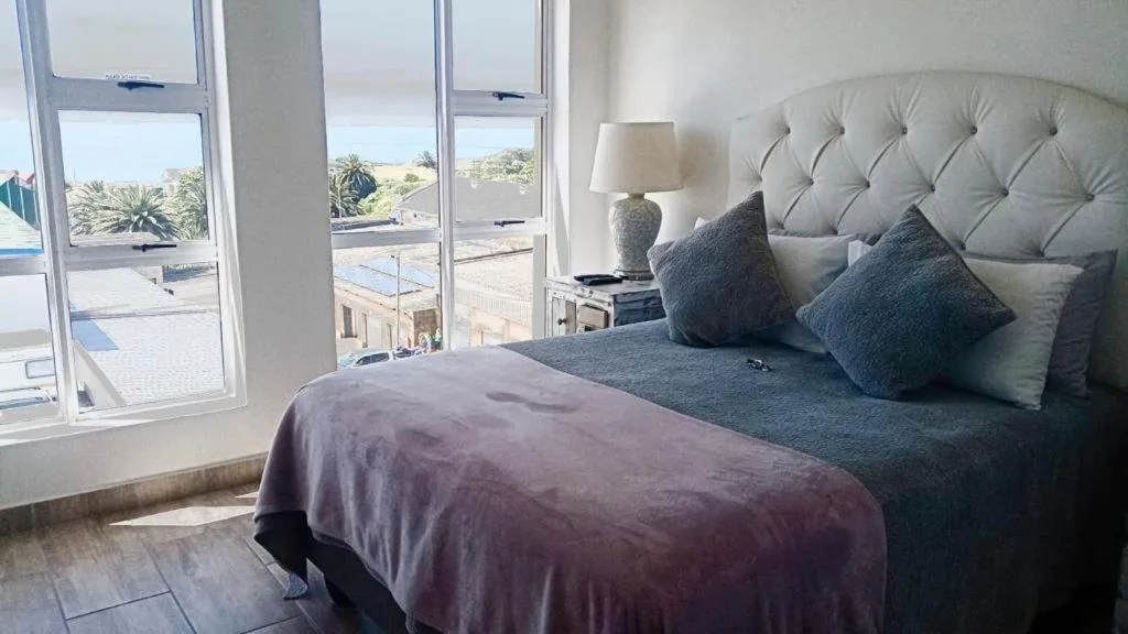 Spacious bedroom with ocean view windows and upholstered headboard
