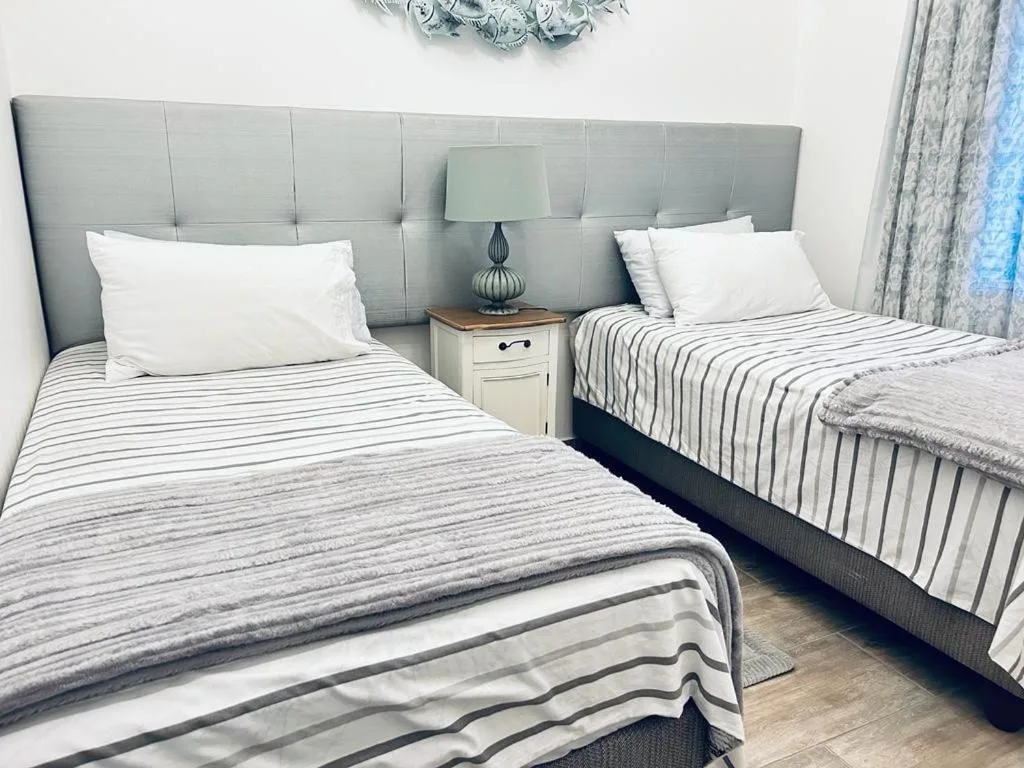 Twin bedroom with grey upholstered headboard and striped bedding