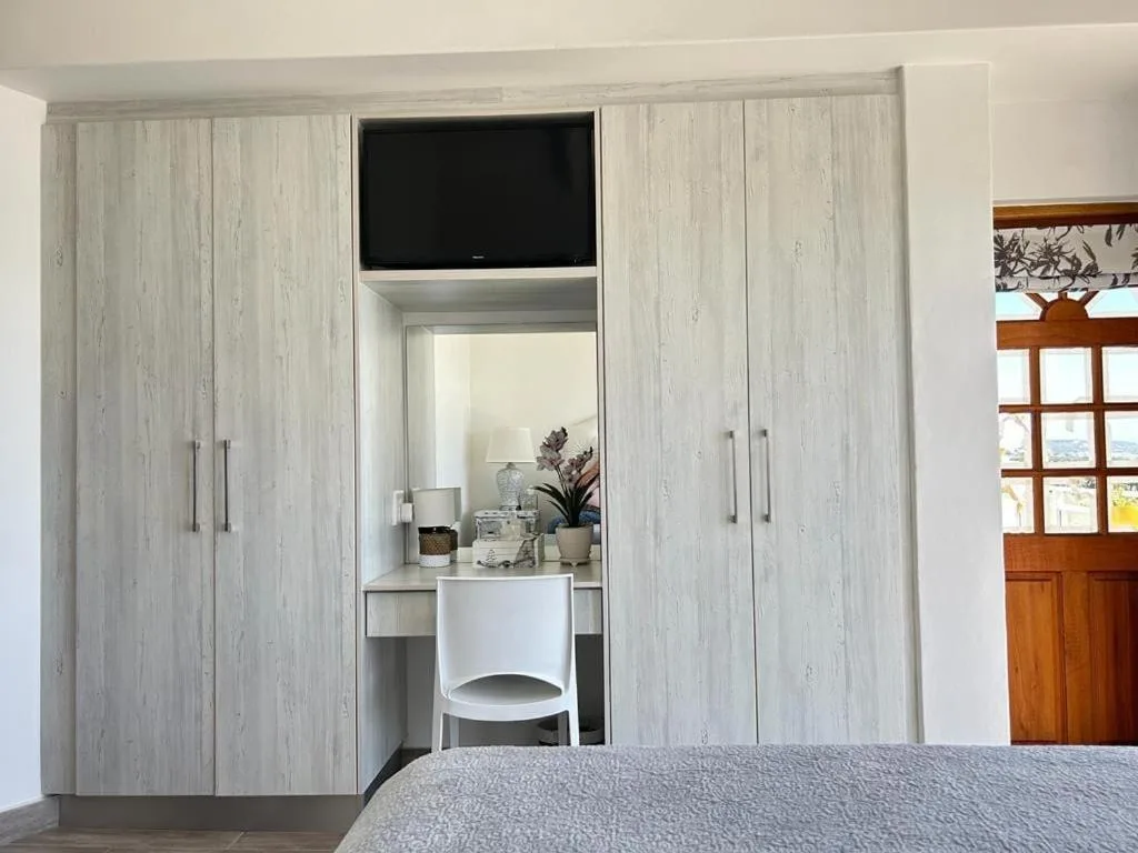 Modern bedroom with built-in wardrobe, vanity desk, and wall-mounted TV