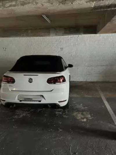 White Volkswagen parked in covered garage space with concrete ceiling