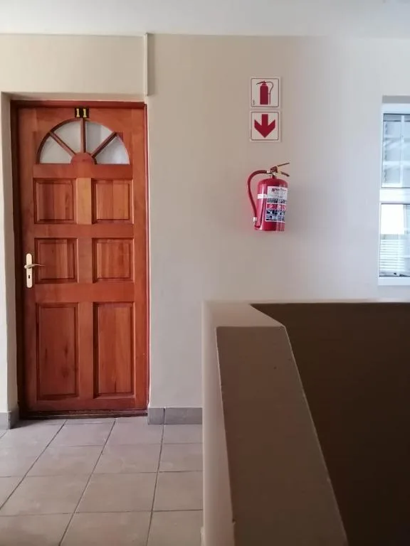 Red wooden door with fanlight and fire safety signage indoors