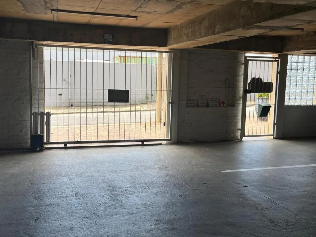 Concrete garage interior with metal security gate and barred doors