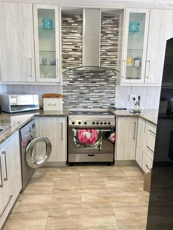 Modern kitchen with white cabinetry, stainless steel stove, and mosaic backsplash