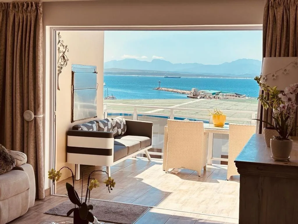 Panoramic ocean and mountain vista from expansive seaside apartment balcony