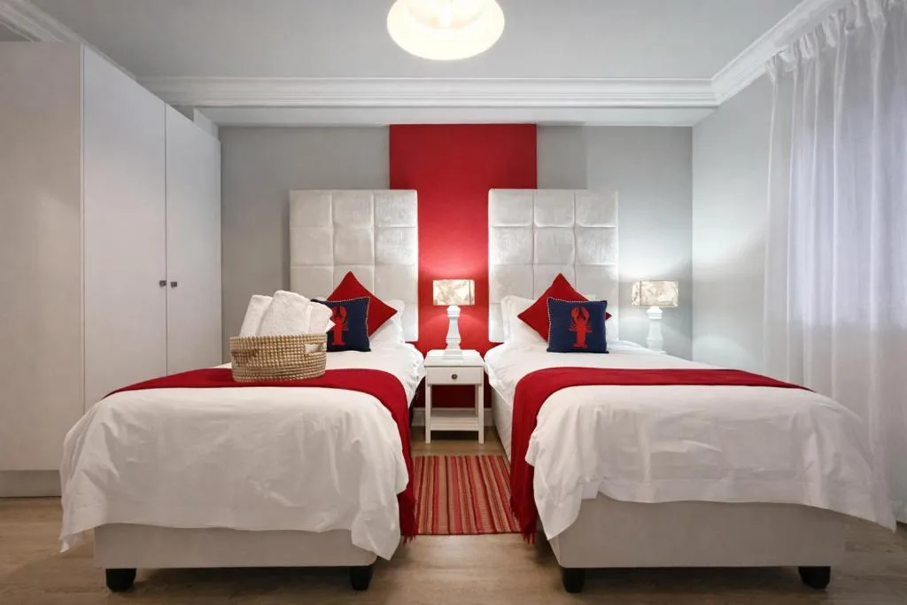 Twin bedroom with red accents, white bedding, and modern headboards