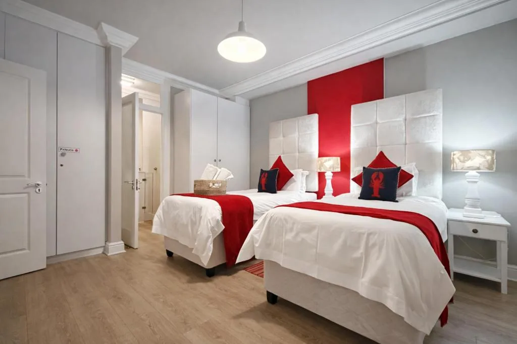 Modern bedroom with twin beds, red accent wall, and contemporary furnishings
