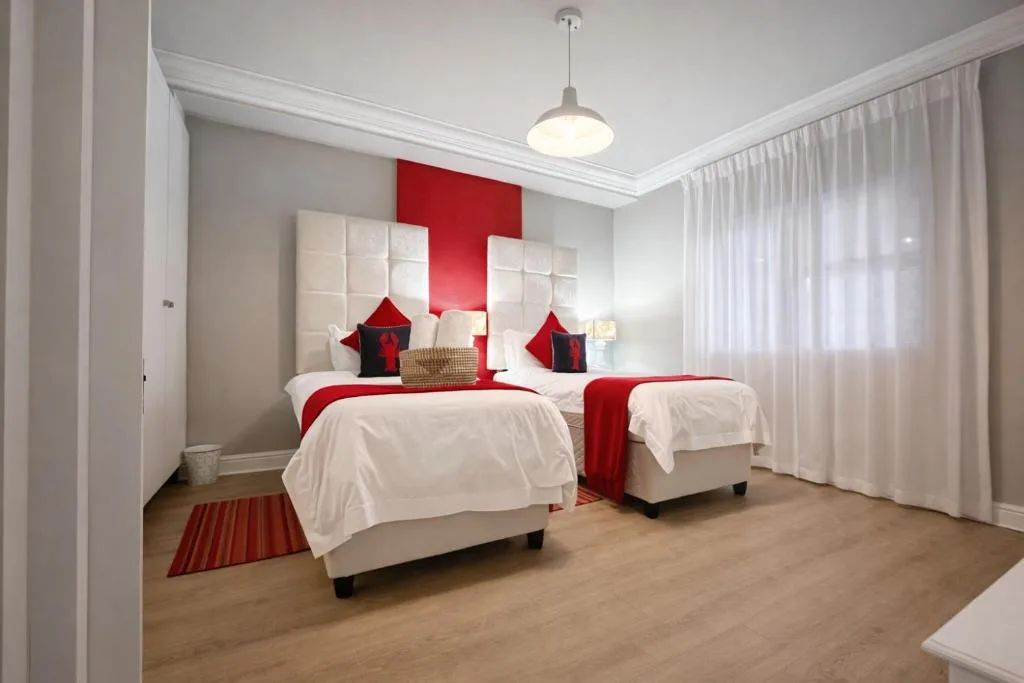 Modern bedroom with twin beds, red accents, and white upholstered headboards
