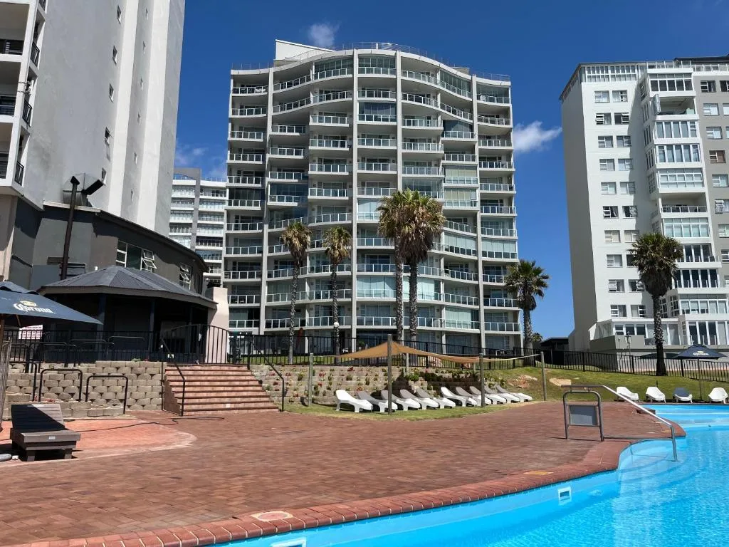 Multi-story beachfront apartment building with palm trees and pool area