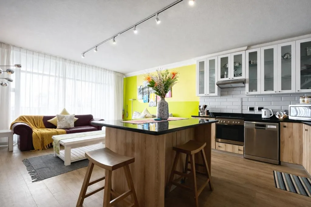 Modern kitchen with island, wooden cabinetry, and open-plan lounge area