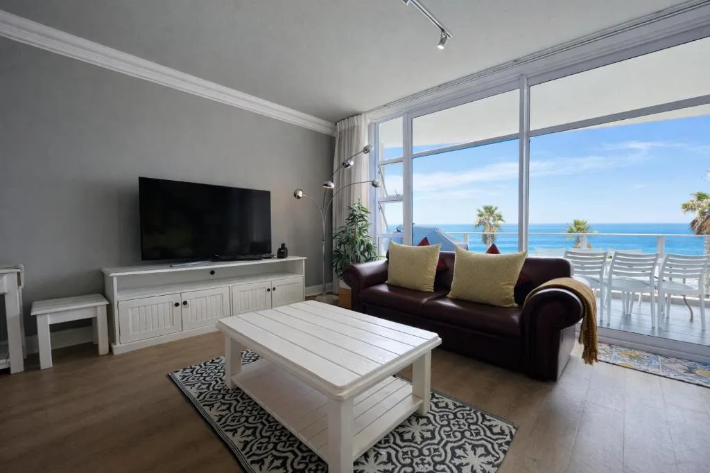 Spacious lounge with ocean view, dark sofa, TV, and modern décor