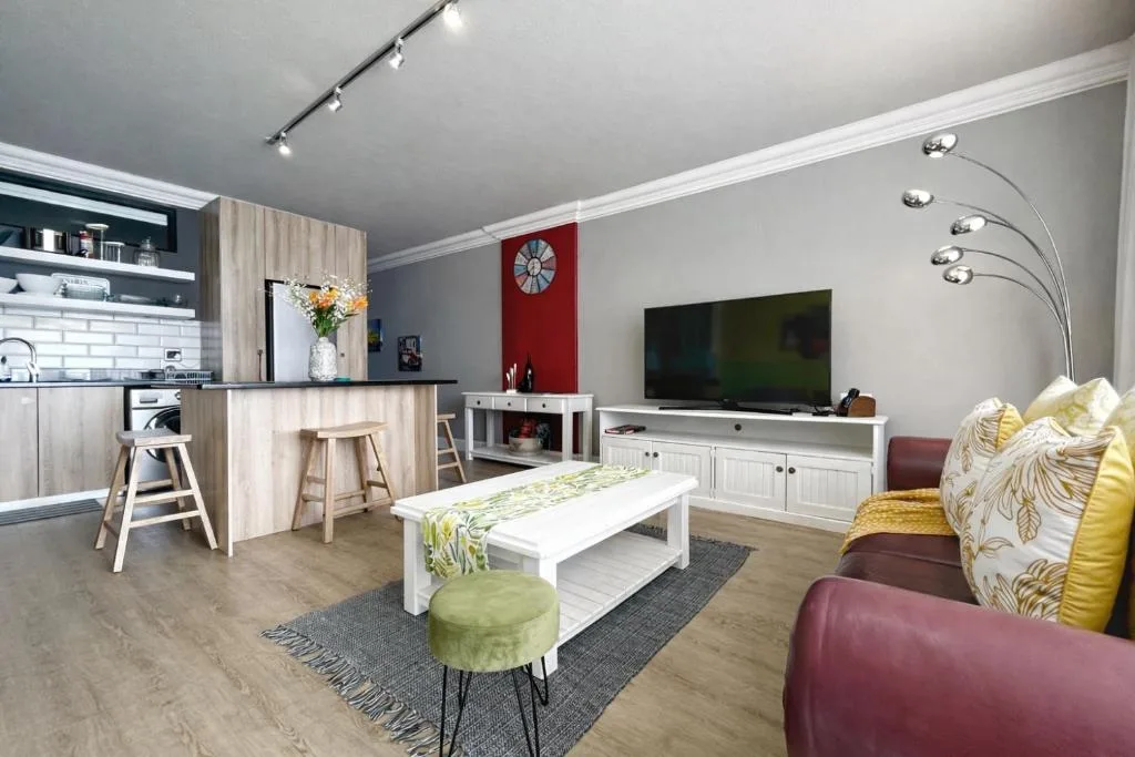 Modern open-plan lounge with burgundy sofa, flat-screen TV, and contemporary furnishings