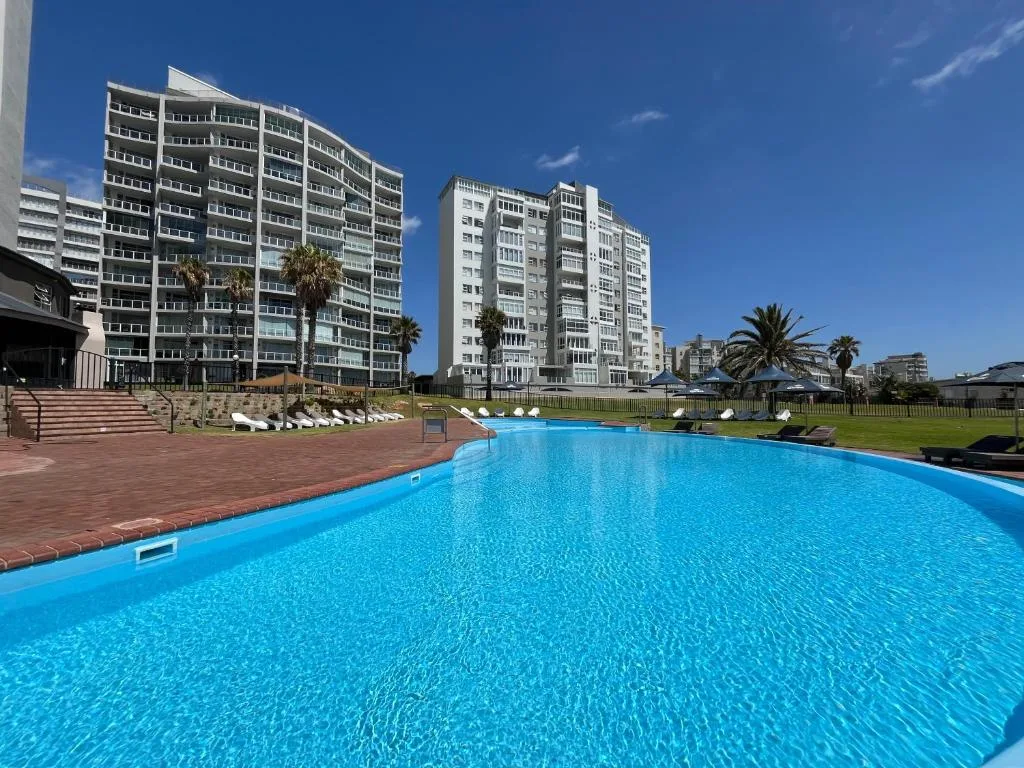 Large sparkling blue swimming pool with apartment buildings and manicured lawns
