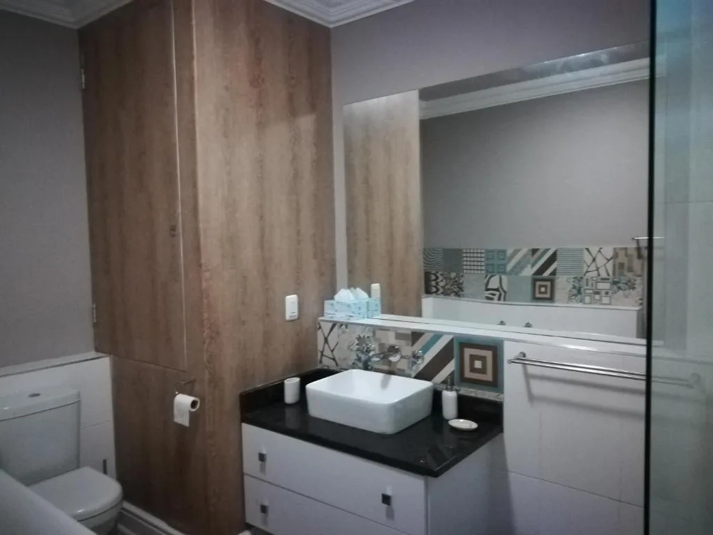 Modern bathroom with white vanity, black countertop, and patterned tile backsplash
