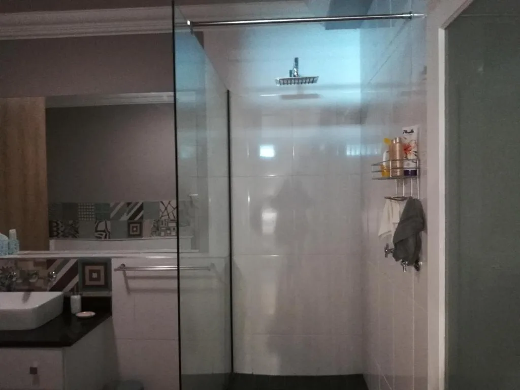 Modern bathroom with walk-in shower, rainfall showerhead, and vanity sink