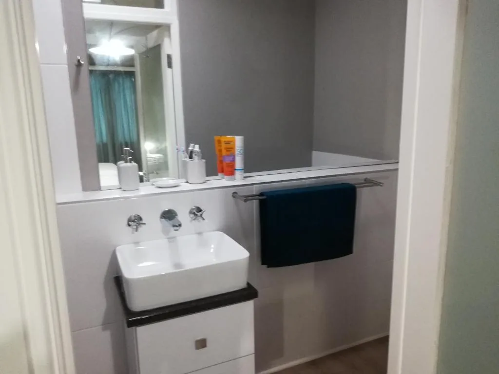 Modern bathroom with white rectangular sink, mirror, and black towel rack
