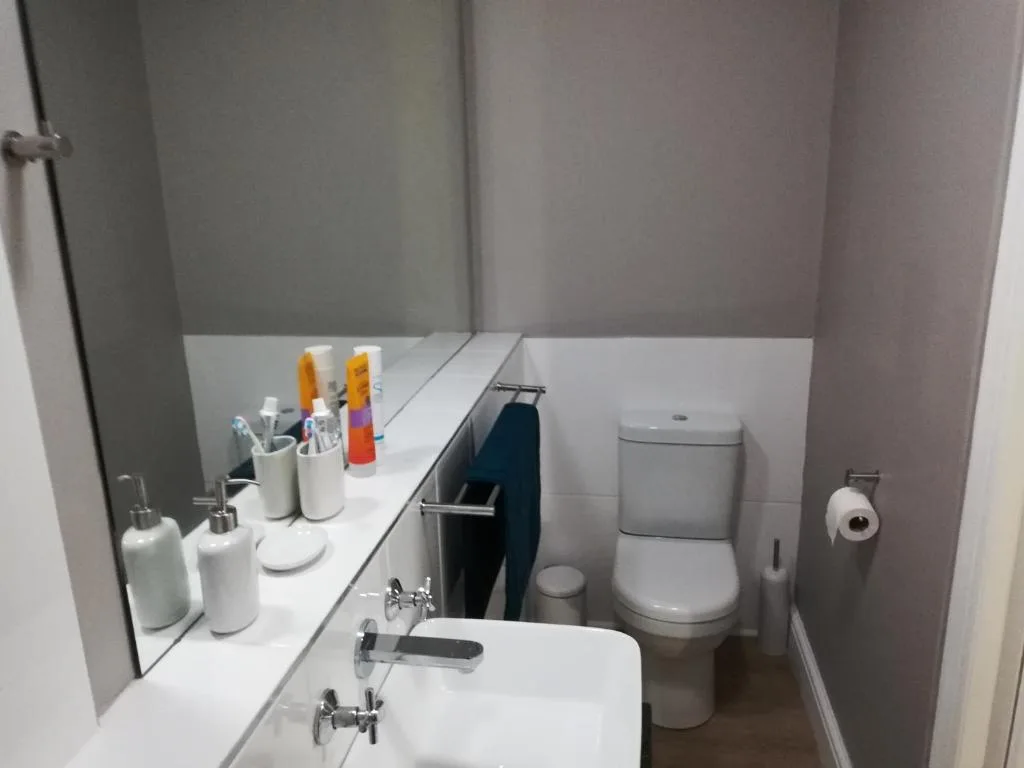 Clean modern bathroom with white vanity, toilet, and organized toiletries